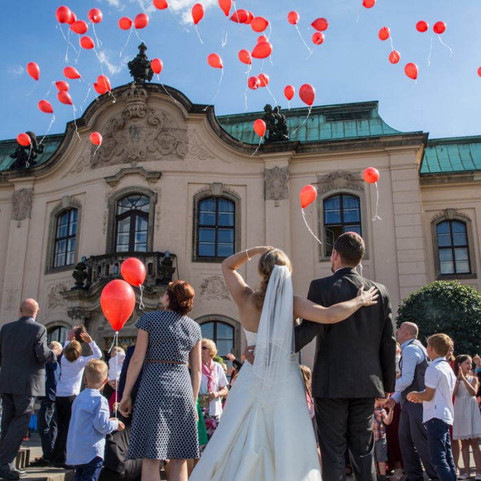 Hochzeitsgesellschaft lässt rote Luftballons in den Himmel steigen