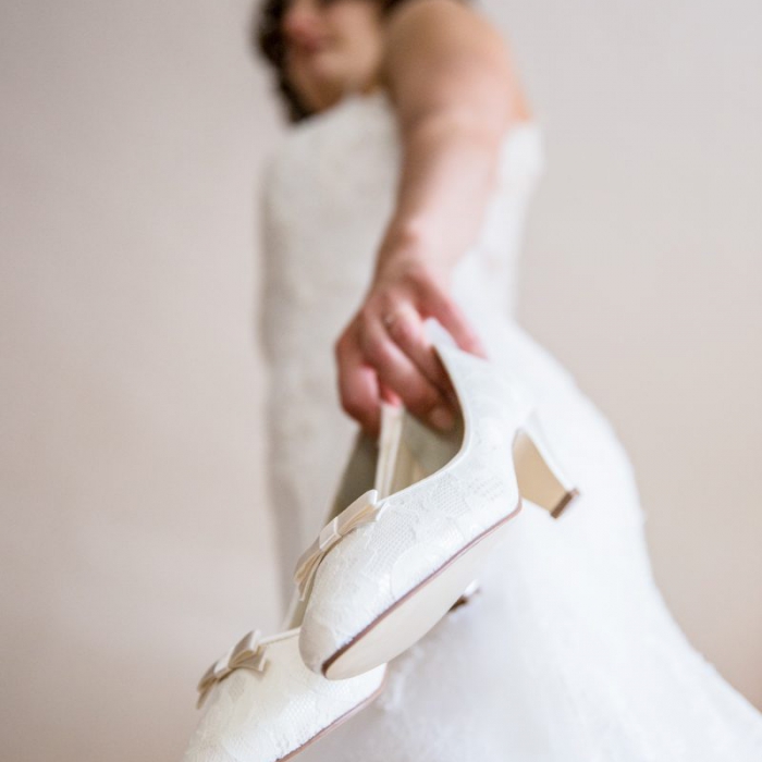 Braut hält Hochzeitsschuhe in der Hand