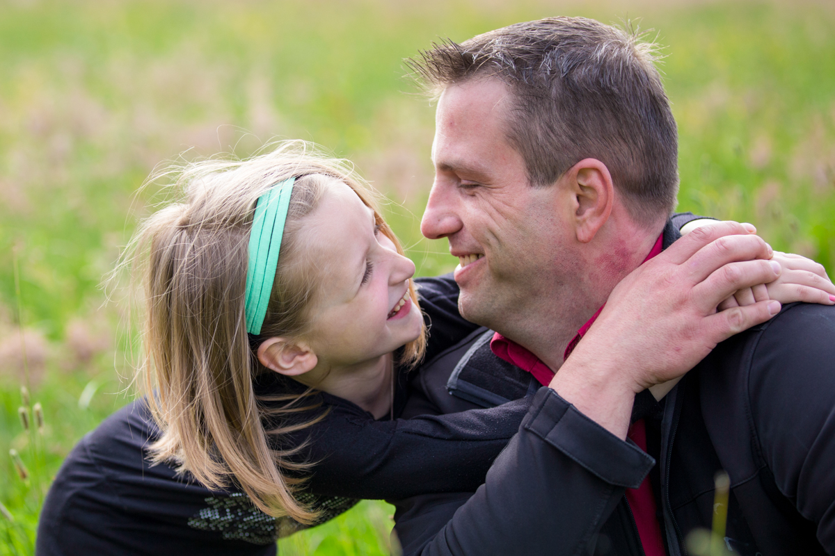 Vater und Tochter umarmen sich auf Blumenwiese